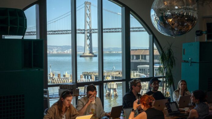 People work at a space called Shack15 inside the Ferry Building in San Francisco, with a view of the San Francisco–Oakland Bay Bridge, on May 8, 2025. Artificial intelligence has ushered in an era of what insiders in the nation’s innovation capital call “hard tech.” (Loren Elliott/The New York Times)